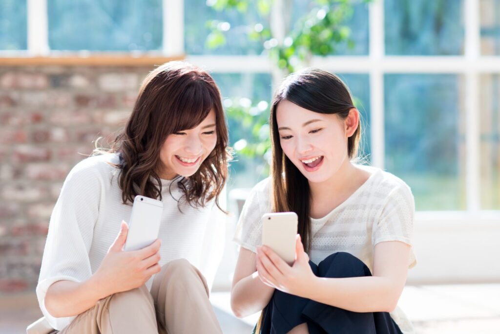 スマートフォンをのぞき込む女性2人